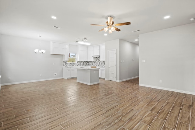 unfurnished living room with ceiling fan with notable chandelier, light wood-style flooring, visible vents, and recessed lighting