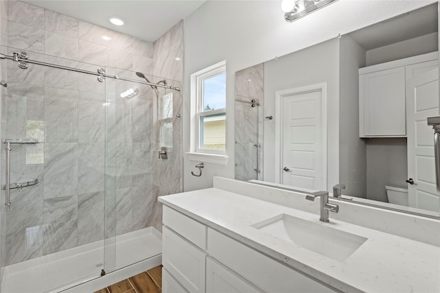 bathroom featuring toilet, a stall shower, wood finished floors, and vanity