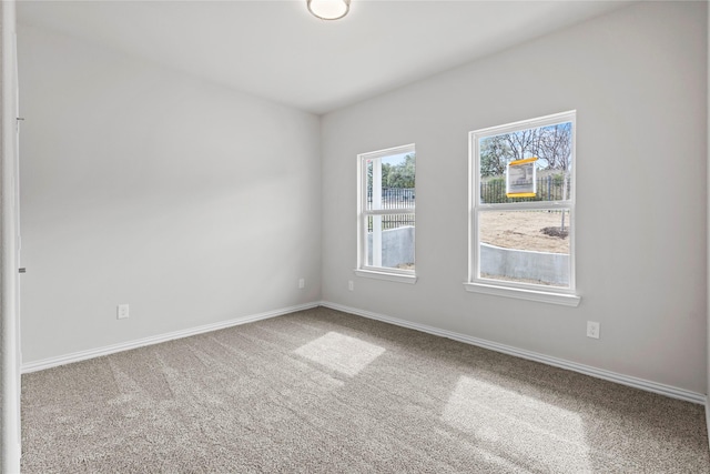 carpeted empty room featuring baseboards