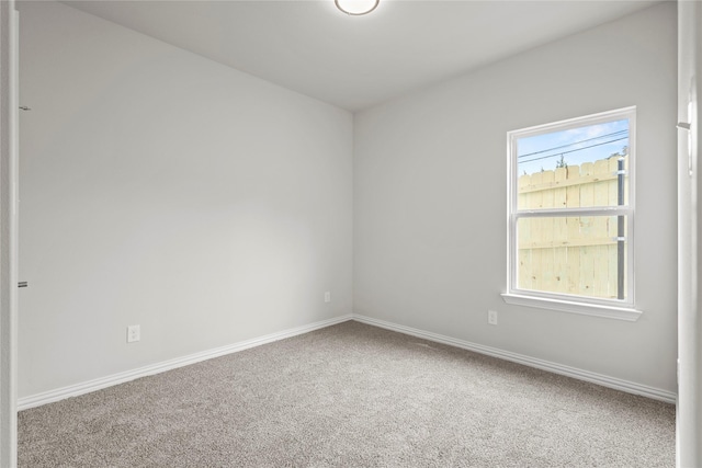 carpeted spare room featuring a wealth of natural light and baseboards