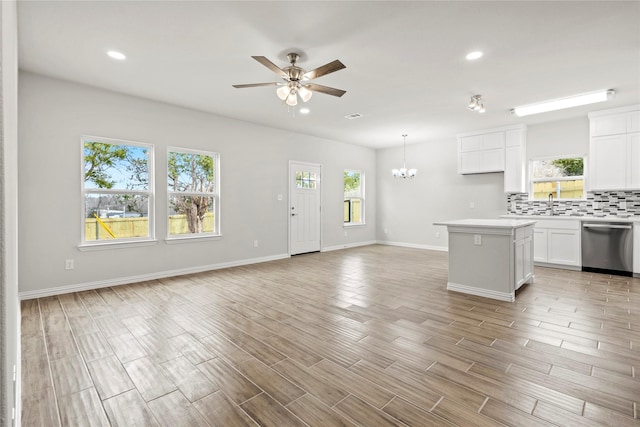 kitchen featuring open floor plan, white cabinetry, dishwasher, and decorative backsplash