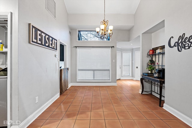 tiled entrance foyer featuring baseboards, a towering ceiling, visible vents, and an inviting chandelier