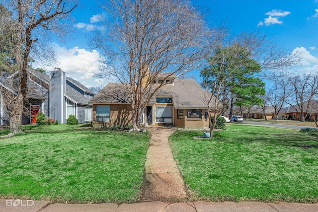 view of front facade with brick siding, roof with shingles, and a front yard