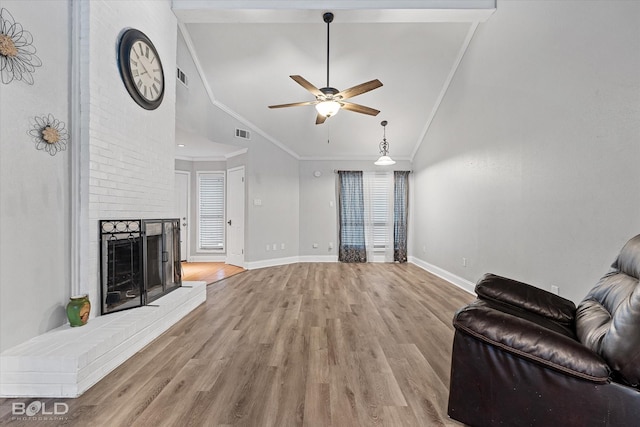 living area with lofted ceiling, light wood-style flooring, a fireplace, and visible vents