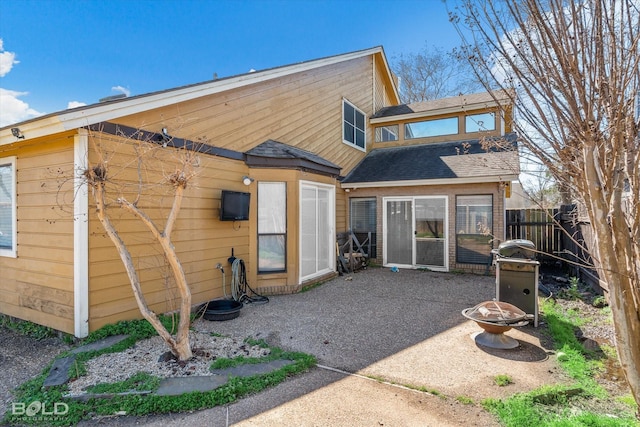 rear view of house with a patio, an outdoor fire pit, a shingled roof, and fence