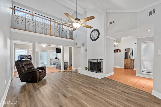 living area with beam ceiling, a fireplace, wood finished floors, and visible vents