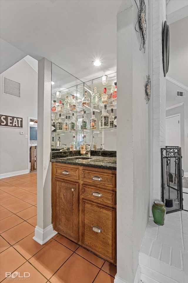 bar with light tile patterned floors, indoor wet bar, a sink, and visible vents