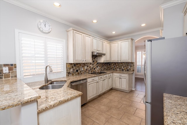 kitchen with arched walkways, appliances with stainless steel finishes, a sink, and tasteful backsplash