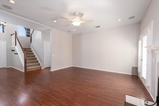 unfurnished living room featuring ceiling fan, a fireplace, wood finished floors, visible vents, and stairway