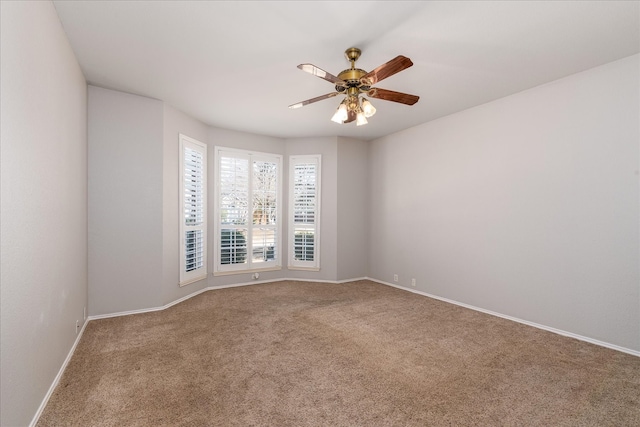 carpeted spare room with a ceiling fan and baseboards