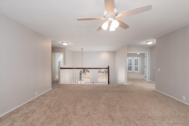 spare room with ceiling fan, carpet, and baseboards