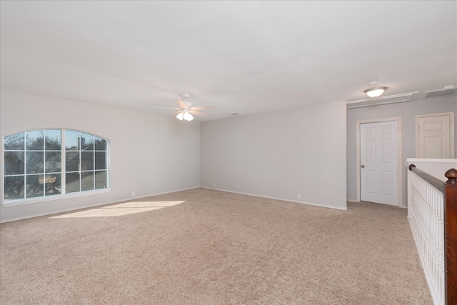 spare room featuring attic access, light carpet, visible vents, and a ceiling fan