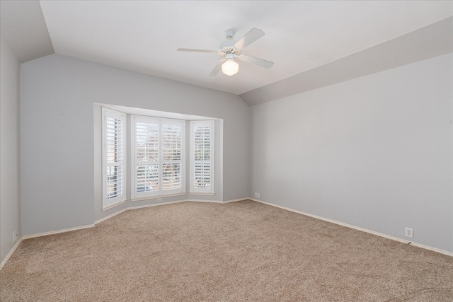 empty room featuring carpet flooring, vaulted ceiling, baseboards, and ceiling fan