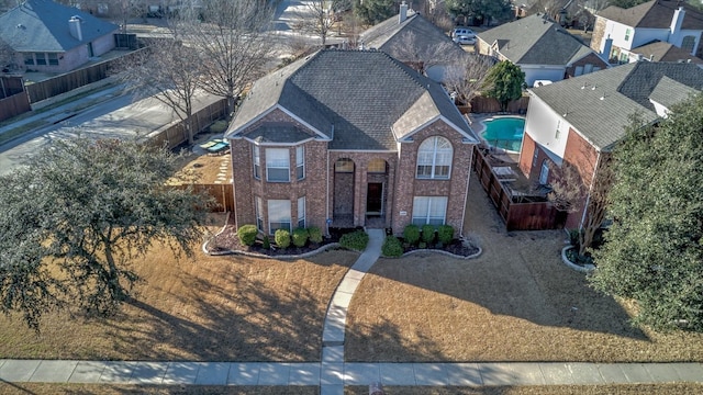 view of front of house featuring a shingled roof, a residential view, fence, and brick siding