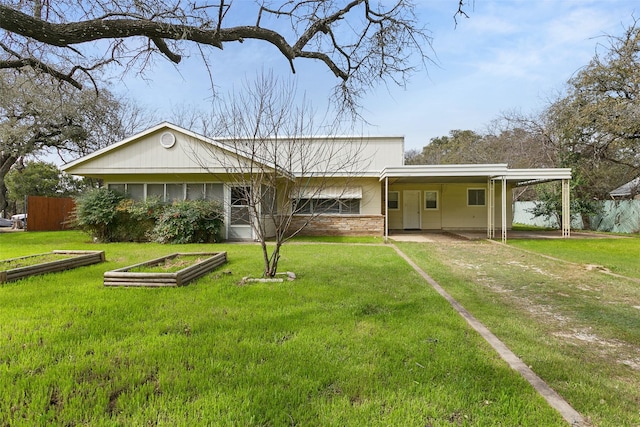 view of front of property with driveway, fence, a front lawn, a carport, and brick siding