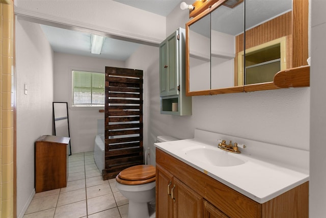 bathroom with a tub to relax in, tile patterned flooring, vanity, and toilet