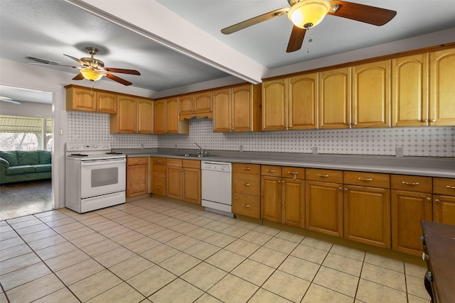 kitchen with white appliances, a sink, visible vents, tasteful backsplash, and brown cabinetry