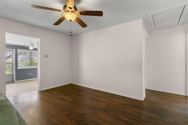 spare room featuring attic access, baseboards, and wood finished floors