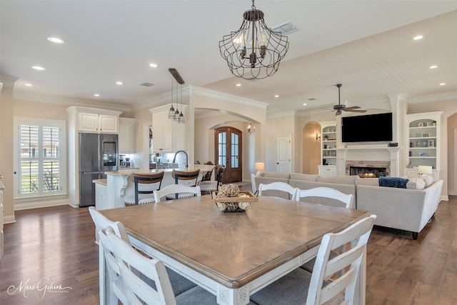 dining space with arched walkways, a warm lit fireplace, recessed lighting, dark wood-style flooring, and visible vents