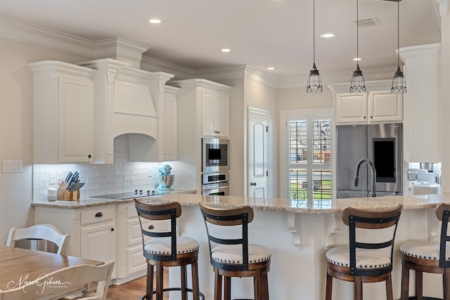 kitchen featuring appliances with stainless steel finishes, white cabinets, backsplash, and a breakfast bar area