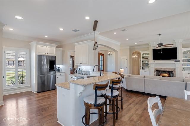 kitchen with light stone counters, arched walkways, stainless steel appliances, dark wood-type flooring, and a sink