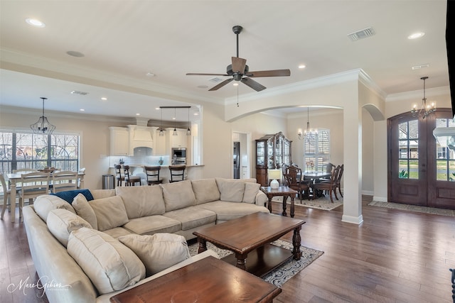 living room featuring arched walkways, dark wood-style flooring, visible vents, and baseboards