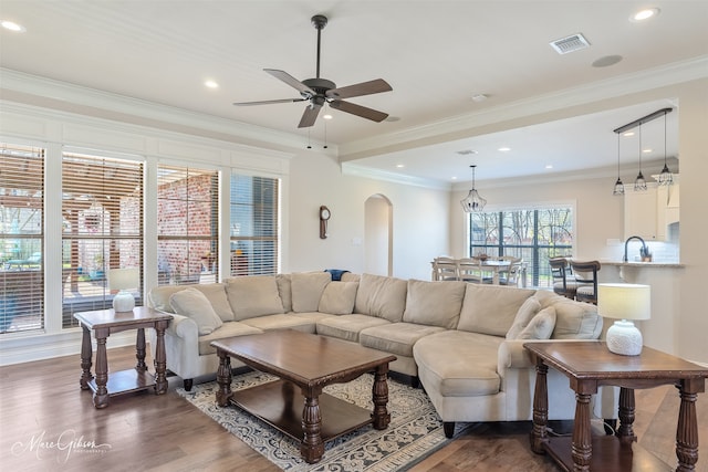 living room with ornamental molding, arched walkways, dark wood-style flooring, and visible vents