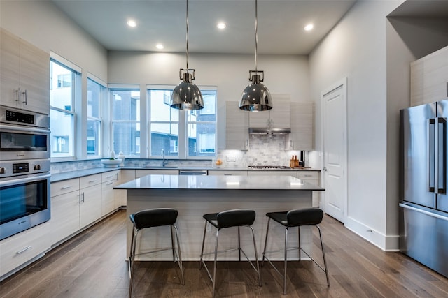 kitchen with decorative backsplash, modern cabinets, appliances with stainless steel finishes, a breakfast bar area, and a sink