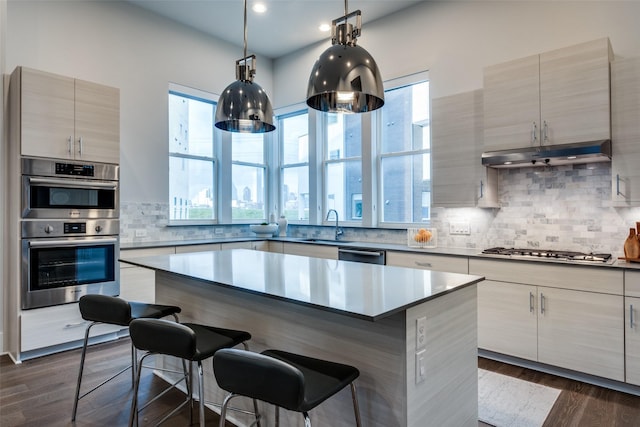 kitchen featuring modern cabinets, a breakfast bar area, stainless steel appliances, under cabinet range hood, and a sink