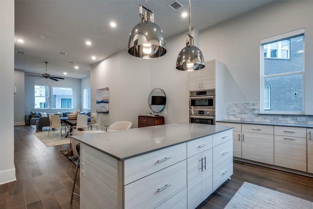 kitchen with visible vents, modern cabinets, dark wood-style flooring, stainless steel double oven, and backsplash