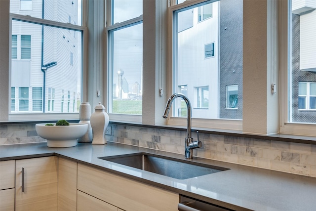 kitchen featuring light brown cabinetry, dark countertops, a sink, and a healthy amount of sunlight