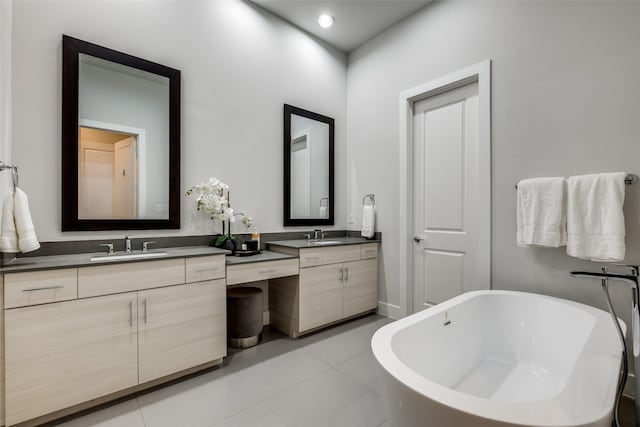 bathroom featuring tile patterned flooring, a freestanding tub, and vanity