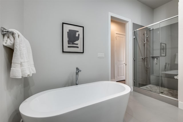 full bath featuring a stall shower, a freestanding tub, a spacious closet, and tile patterned floors