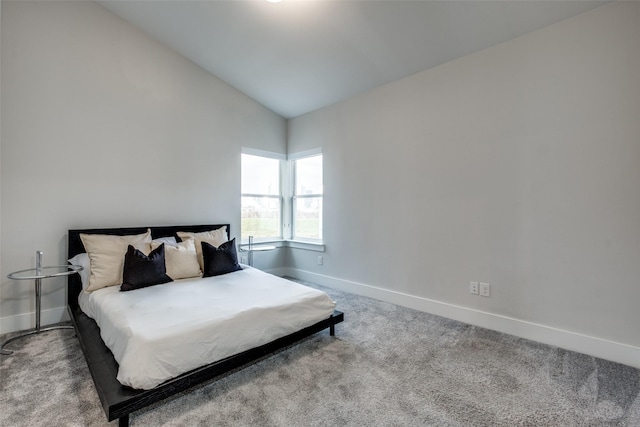 carpeted bedroom featuring lofted ceiling and baseboards