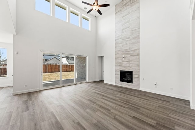 unfurnished living room featuring visible vents, a ceiling fan, a high end fireplace, wood finished floors, and baseboards