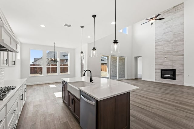 kitchen with visible vents, a tiled fireplace, appliances with stainless steel finishes, wood finished floors, and a sink