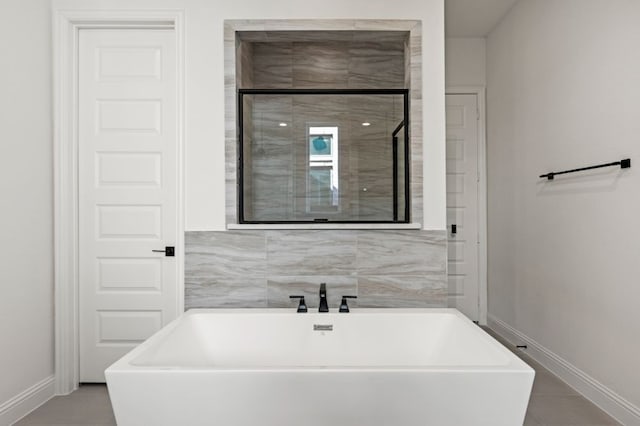 full bathroom featuring tile patterned flooring, a freestanding tub, and baseboards