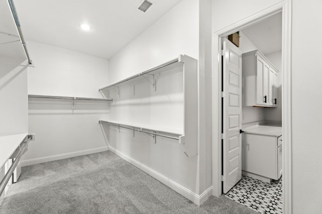 walk in closet with visible vents and light carpet