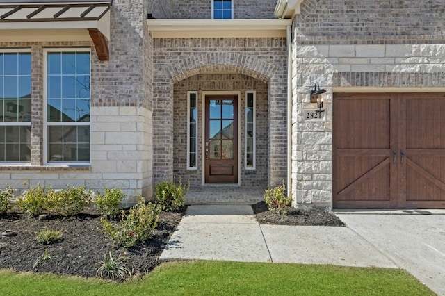 view of exterior entry with a garage and brick siding