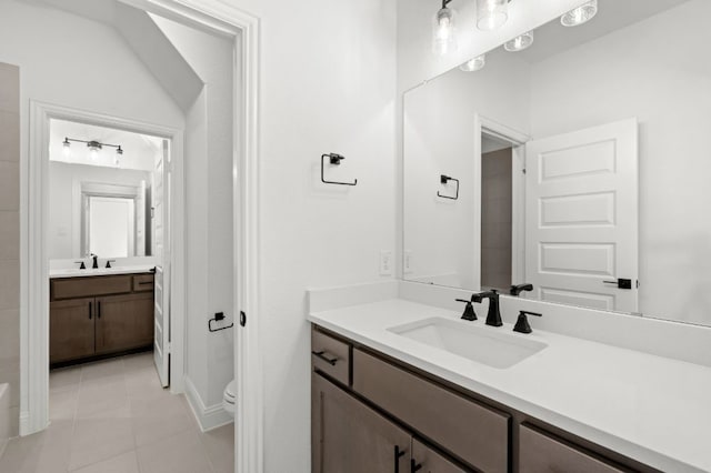 bathroom featuring tile patterned flooring, two vanities, a sink, and toilet