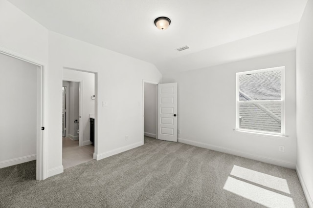 unfurnished bedroom featuring carpet, visible vents, vaulted ceiling, and baseboards