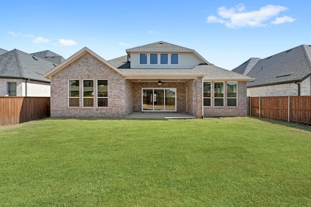 rear view of house with a yard, brick siding, and a fenced backyard