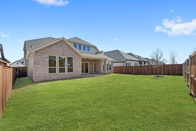 back of house with a ceiling fan, brick siding, a yard, and a fenced backyard