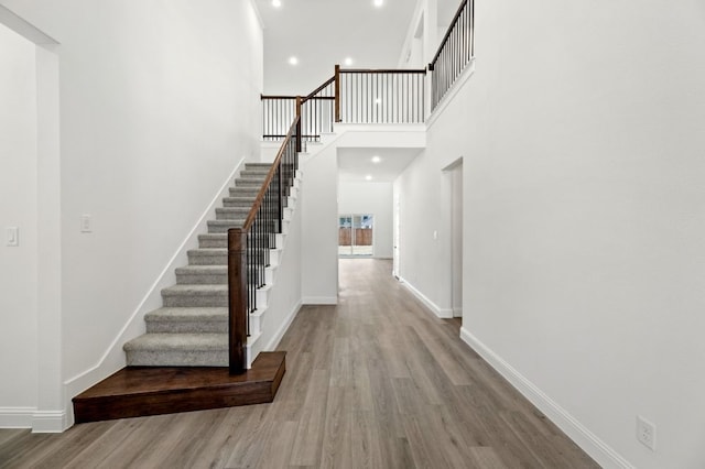 interior space featuring a high ceiling, baseboards, wood finished floors, and recessed lighting