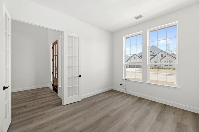 spare room featuring plenty of natural light, wood finished floors, and visible vents