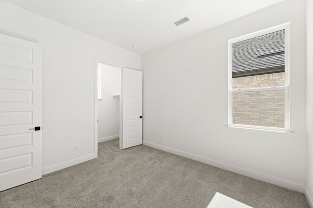 unfurnished bedroom featuring carpet, a walk in closet, visible vents, and baseboards