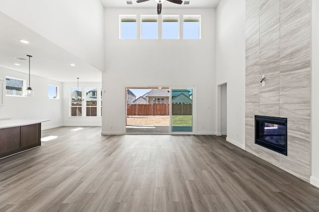 unfurnished living room with a tiled fireplace, wood finished floors, and a healthy amount of sunlight