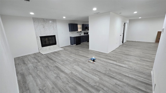 unfurnished living room featuring recessed lighting, a fireplace, visible vents, baseboards, and light wood-type flooring