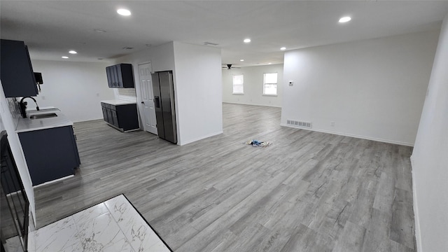 kitchen with visible vents, light wood-style flooring, open floor plan, light countertops, and a sink