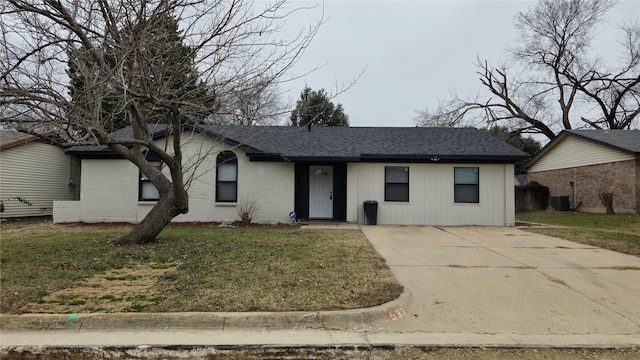 ranch-style house featuring a shingled roof, brick siding, a front lawn, and central AC unit